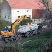 Schutt wird mit Bagger auf Transporter verladen